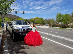 15 yrs old girl posing during her quinceanera celebration aka quinceañera, happy riding on white hummer limousine in San Diego.
