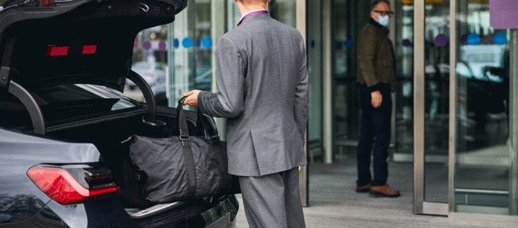 Driver in an elegant suit looking at his passenger standing at the airport terminal entrance at san diego international airport on the way to LAX