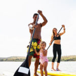 Portrait of couple and toddler daughter standup paddleboarding, Carlsbad, California, USA