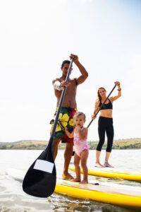 Portrait of couple and toddler daughter standup paddleboarding, Carlsbad, California, USA