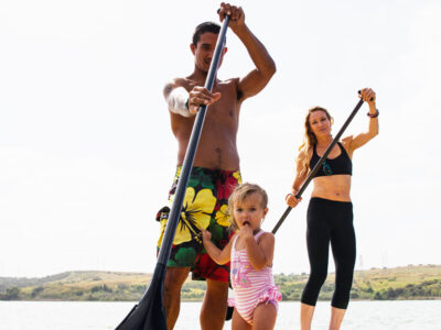 Portrait of couple and toddler daughter standup paddleboarding, Carlsbad, California, USA