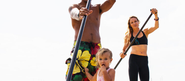 Portrait of couple and toddler daughter standup paddleboarding, Carlsbad, California, USA