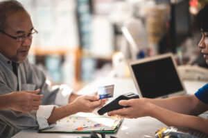 Senior customer paying garage for services and repair work using debit and credit card